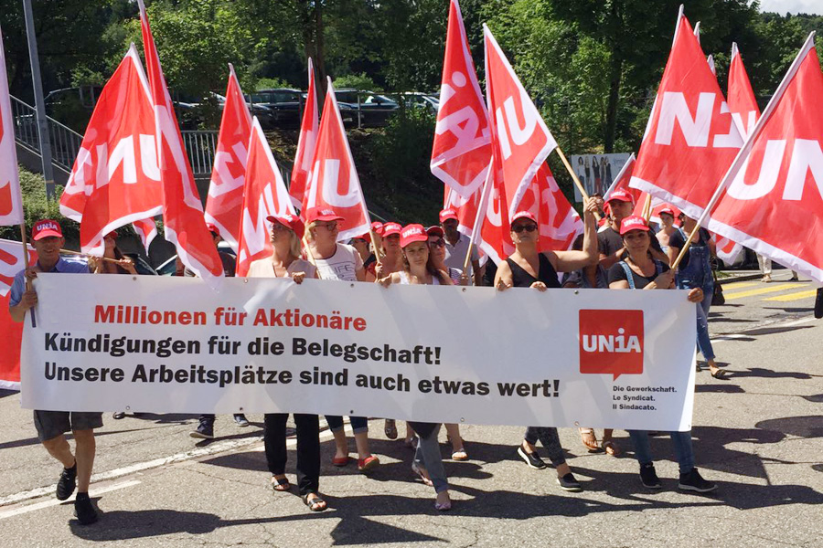 Gruppo di manifestanti con bandiere di Unia e striscione.