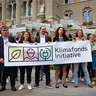 Des représentant-e-s du Parti socialiste, des Verts et Vertes et du syndicat Unia tiennent une banderole à l’effigie de l’initiative pour le fonds climat, devant le Palais fédéral.