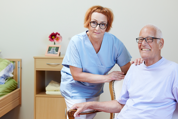 Pflegende mit einem Bewohner lächeln in die Kamera