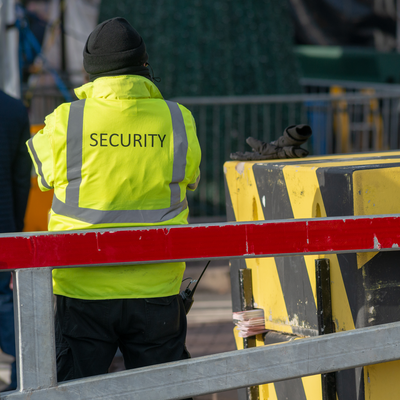 Un agent de sécurité vêtu d'un gilet fluorescent surveille un chantier.