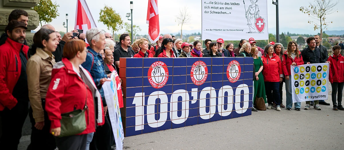 Die Unia und weitere Organisationen reichen vor der Bundeskanzlei rund 100'000 Unterschriften gegen den Angriff auf die Mindestlöhne ein. Im Zentrum steht eine grosse Mauer aus Karton, auf der die Zahl «100'000» steht.