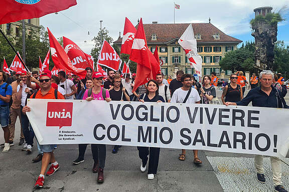 Lavoratrici e lavoratori con striscione: voglio vivere col mio salario!