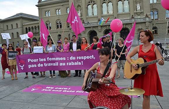 Action sur la Place fédérale avec beacoup de lila et banderole: Nous en avons assez! Égalité salariale maintenant!
