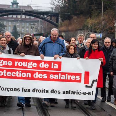 Manifestation syndicale à Berne. Un groupe de personnes, entre eux la présidente d'Unia, Vania Alleva, marche en tenant une banderole avec le message: 