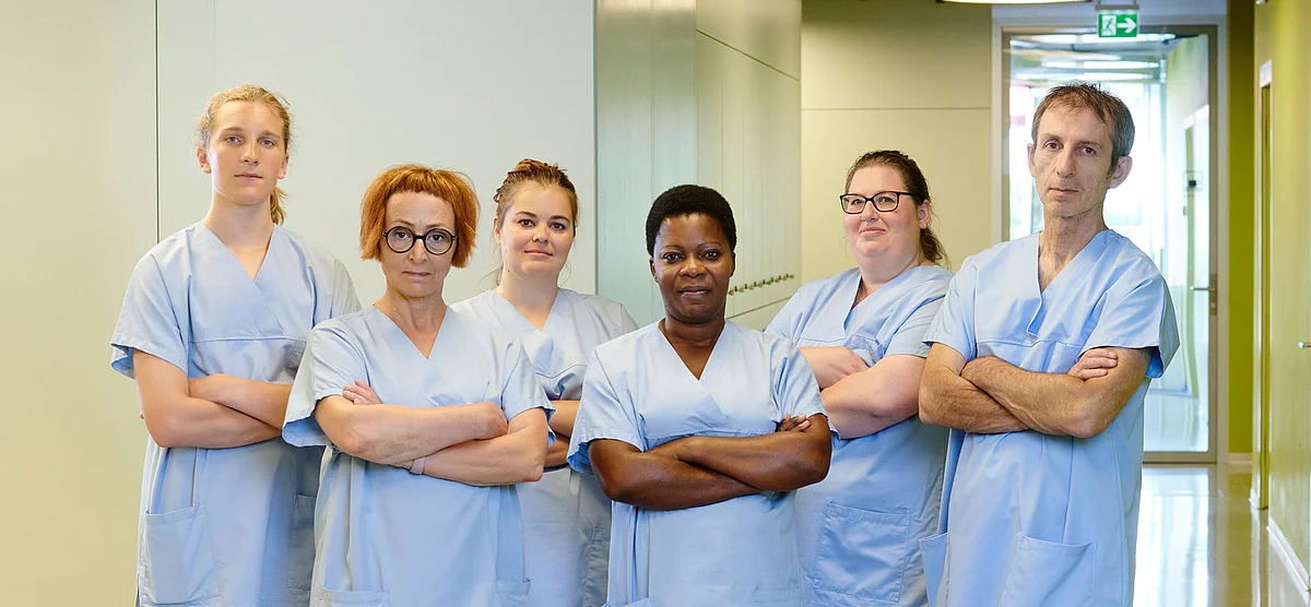 Un gruppo di addetti e addette alle cure con le braccia incrociate.
