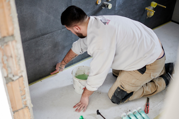 Un peintre à genoux sur le sol occupé à des travaux.