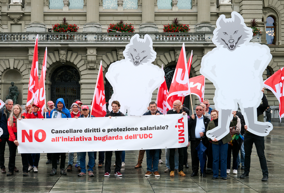 Attivisti di Unia con lupi di cartone e uno striscione davanti al Palazzo federale: «Cancellare diritti e protezione salariale? NO all'iniziativa bugiarda dell'UDC». Foto: Manu Friederich