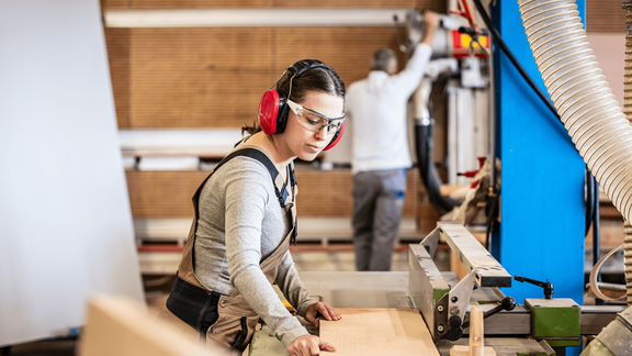 Una falegname lavora il legno con una sega.