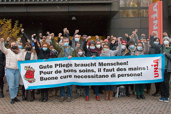 Gruppo di partecipanti alla conferenza professionale del 2021 con striscione: Buone cure necessitano di persone!