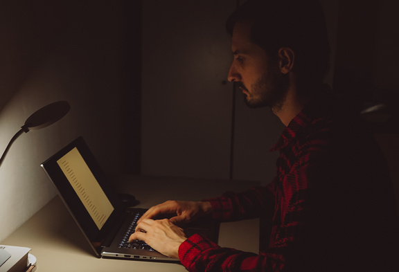 Une personne qui travaille depuis chez soi : on voit sur la table un ordinateur portable, un jouet, une tasse de café entamée et des restes de nourriture.