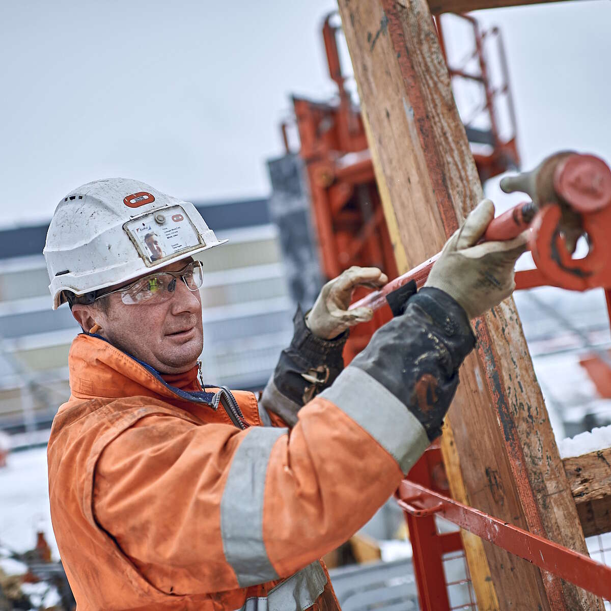 Un travailleur de la construction fixe une barre sur une chantier en hiver.