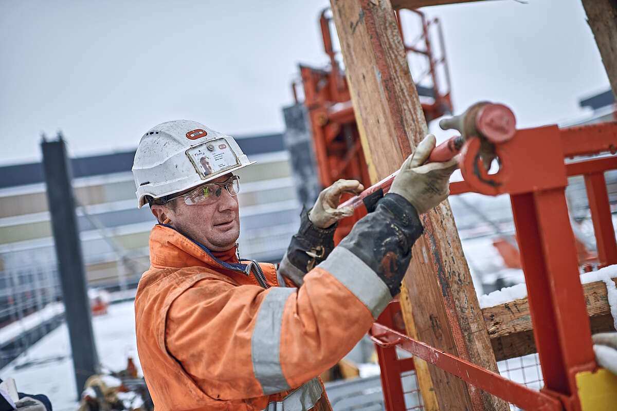 Un travailleur de la construction fixe une barre sur une chantier en hiver.