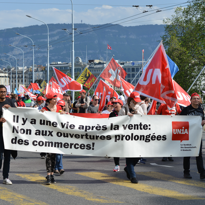 Les membres d’Unia manifestent avec des drapeaux et une banderole contre l’extension des horaires d’ouverture des commerces: 