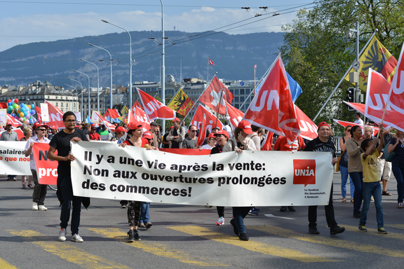 Les membres d’Unia manifestent avec des drapeaux et une banderole contre l’extension des horaires d’ouverture des commerces: 