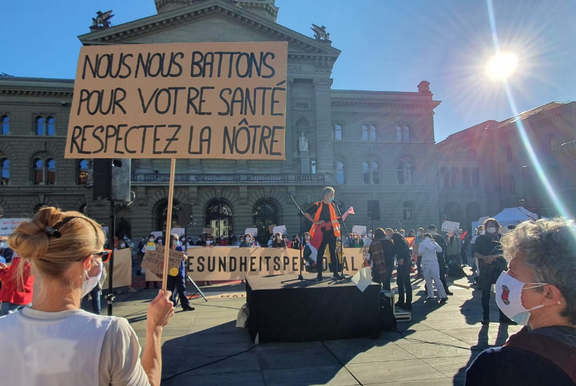  Les soignant-e-s en blouse de travail brandissent des pancartes lors d’une manifestation sur la Place fédérale.