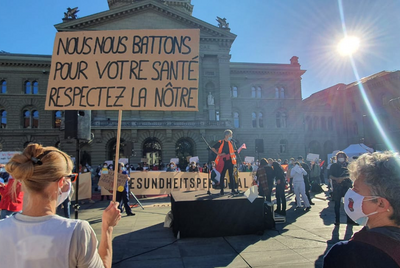  Les soignant-e-s en blouse de travail brandissent des pancartes lors d’une manifestation sur la Place fédérale.