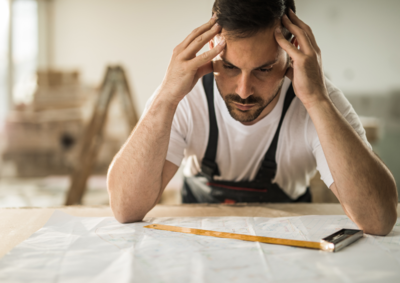 Un homme fatigué en habit de travail se tient la tête