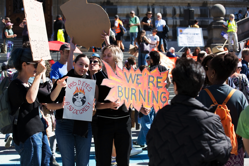 Des manifestant-e-s brandissent des pancartes faites main, dont une avec l’inscription «We are burning».