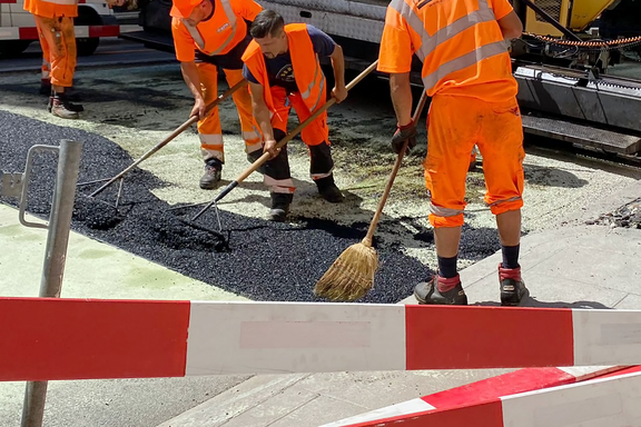 Des travailleurs étalent du goudron sous la canicule