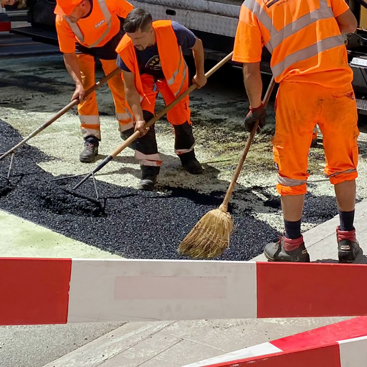 Lavoratori edili che asfaltano una strada sotto il sole cocente