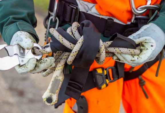 Une personne en tenue de protection tient une corde de sécurité avec un mousqueton. Gros plan sur la sécurité au travail et la protection de la santé.