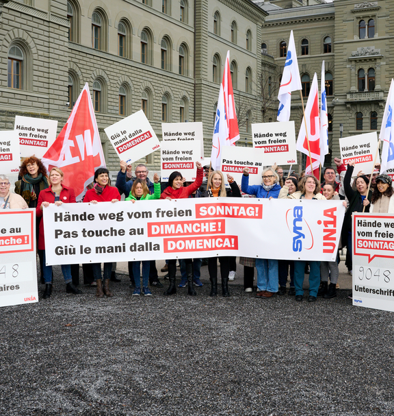 Des gens brandissent une banderole et des affiches avec l'inscription «Pas touche au congé du dimanche» en allemand, en français et en italien.