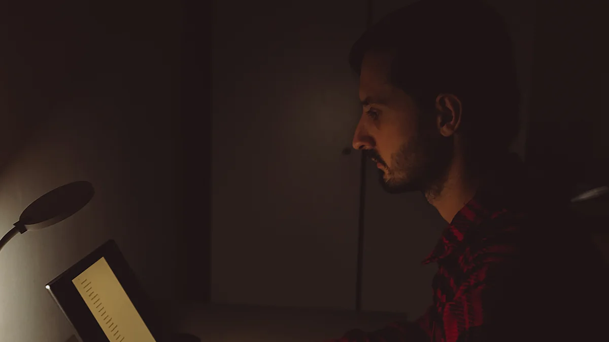 Eine Person, die von zu Hause arbeitet: Auf dem Tisch stehen ein Laptop, ein Spielzeug, eine angebrochene Kaffeetasse und Essensreste.