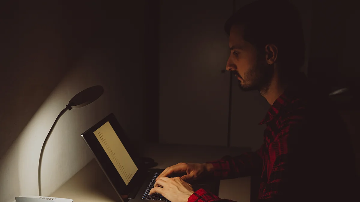 Une personne qui travaille depuis chez soi : on voit sur la table un ordinateur portable, un jouet, une tasse de café entamée et des restes de nourriture.
