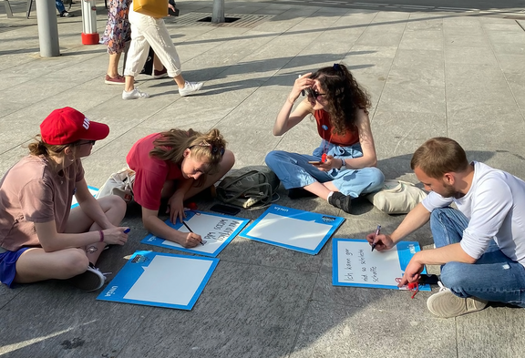 Des soignant-e-s assis par terre inscrivent des slogans sur des panneaux lors d’une action d’Unia.