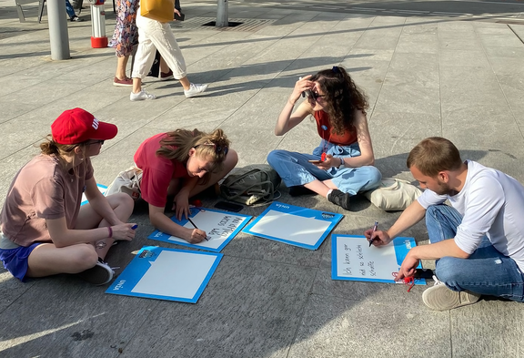 Pflegende beschreiben Bilder am Boden sitzend an einer Unia-Aktion.