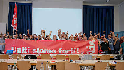 Die Teilnehmenden der Berufskonferenz des Maler- und Gipsergewerbes halten ein Transparent auf dem «Uniti siamo forti!» steht.