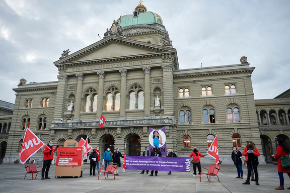 Unia distribue des tracts devant le Palais fédéral, avec une banderole
