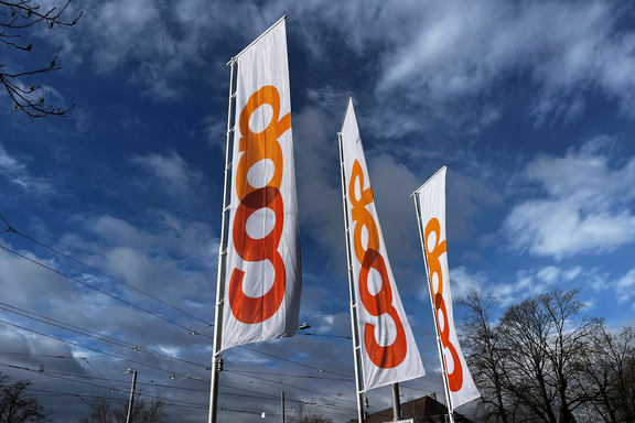 Drei lange Coop-Fahnen im Wind ragen in den Himmel. 
