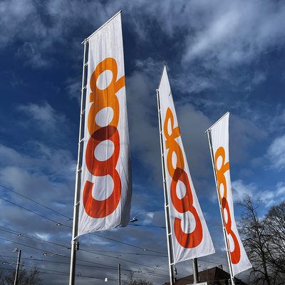 Drei lange Coop-Fahnen im Wind ragen in den Himmel. 