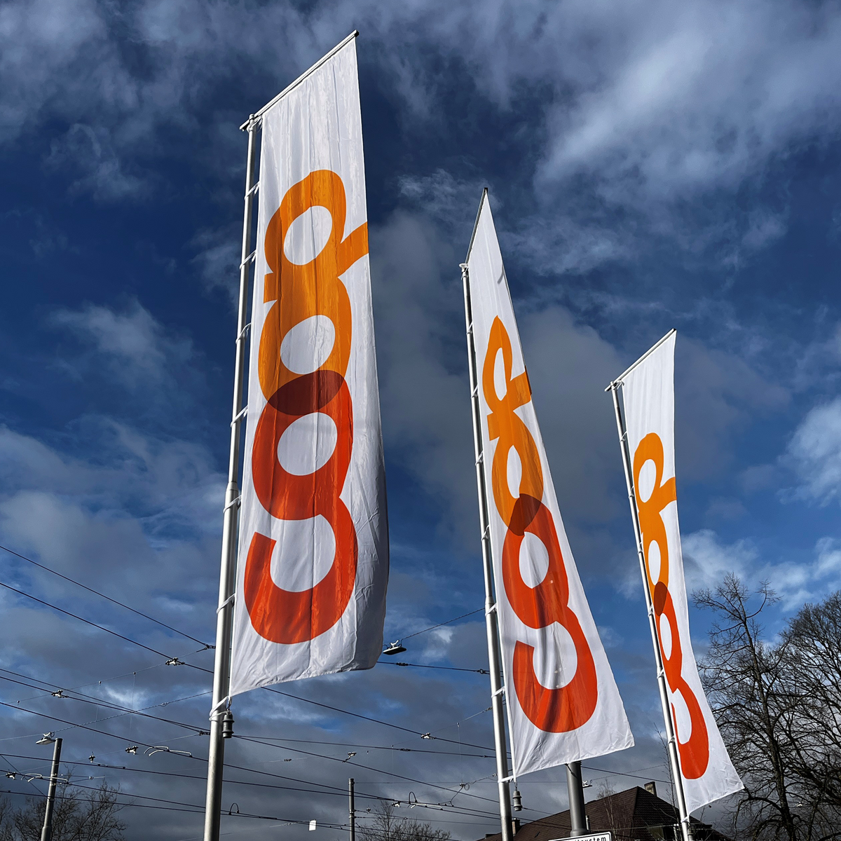 Trois longs drapeaux de Coop flottent dans un ciel bleu