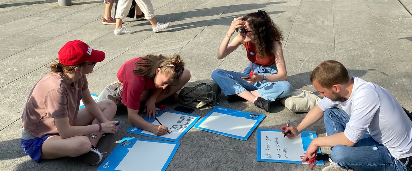 Des soignant-e-s assis par terre inscrivent des slogans sur des panneaux lors d’une action d’Unia.