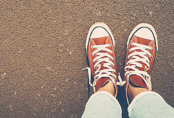 Vista dall'alto di un paio di piedi con Chuck rosse da soli per strada