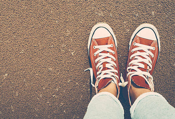 Vue d'en haut d'une paire de pieds en Chucks rouges seules dans la rue