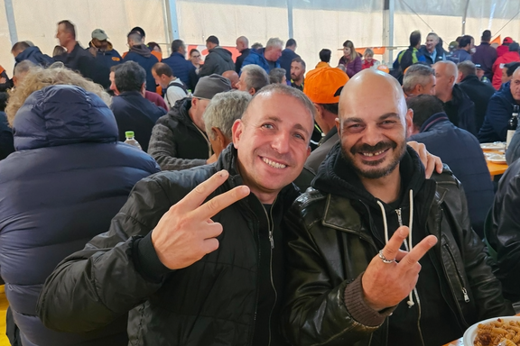 Deux travailleurs de la construction font le signe de la victoire à un rassemblement du syndicat Unia.