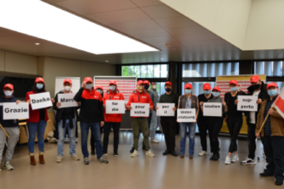 Menschen in einem Raum, die Transparente halten.