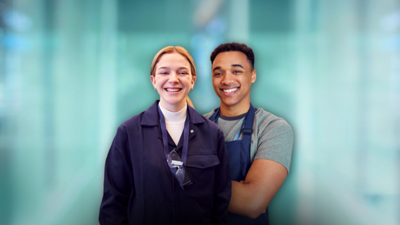 Deux jeunes professionnels en tenue de travail sourient avec assurance devant un arrière-plan moderne et flou.