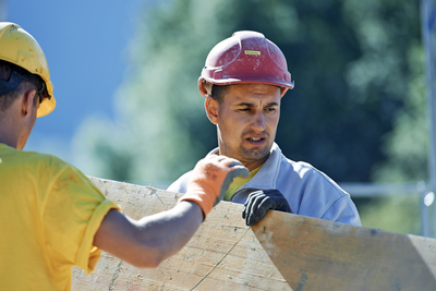 Deux maçons avec panneau de coffrage dans la chaleur estivale