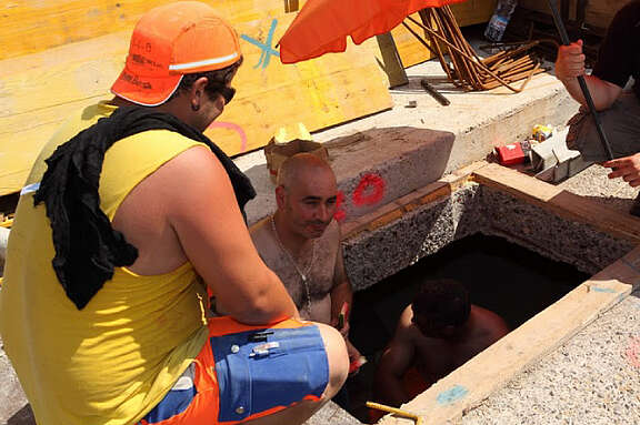 Bauarbeiter kühlen sich im Sommer im Schatten und mit Wasser ab