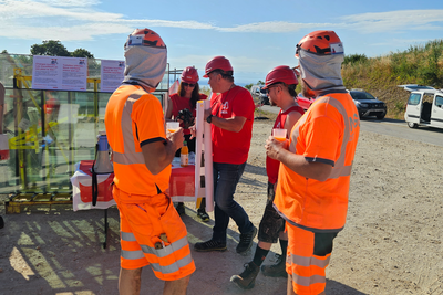 Des ouvriers sur un chantier regardent les syndicalistes installer le stand d'information.