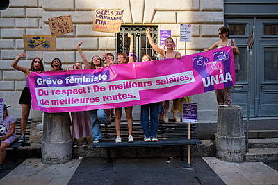 Des jeunes femmes derrière une banderole avec des revendications de la grève féministe