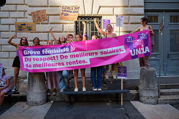 Des jeunes femmes derrière une banderole avec des revendications de la grève féministe