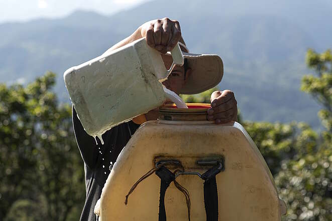 In Costa Rica schüttet ein junger Arbeiter ungeschützt Chemikalien in einen alten Behälter.