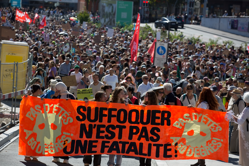 Des jeunes femmes portent une banderole orange avec l’inscription «Suffoquer n’est pas une fatalité», suivies d’une grande foule.