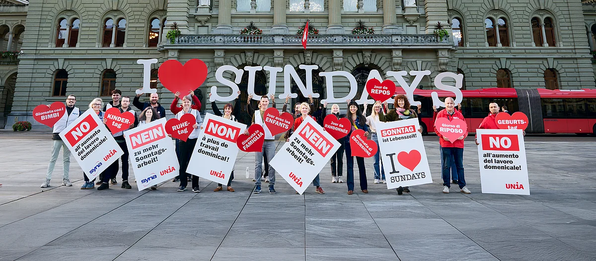 Menschen halten Transparente, Plakate und Buchstaben in die Luft, die den Schriftzug «I love Sundays» bilden.
