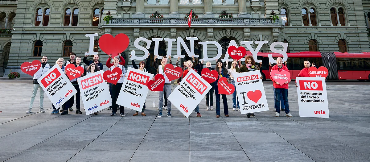 Eine Gruppe von Menschen halten Schilder und Buchstaben in die Luft, die den Schriftzug «I love Sundays» bilden.
